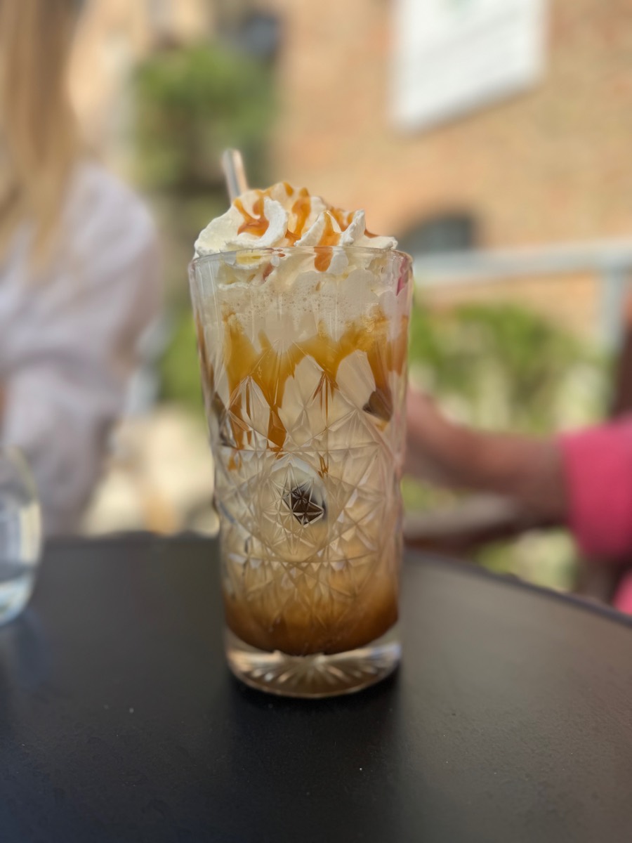 Iced coffee with caramel and cream in a cut glass on the terrace