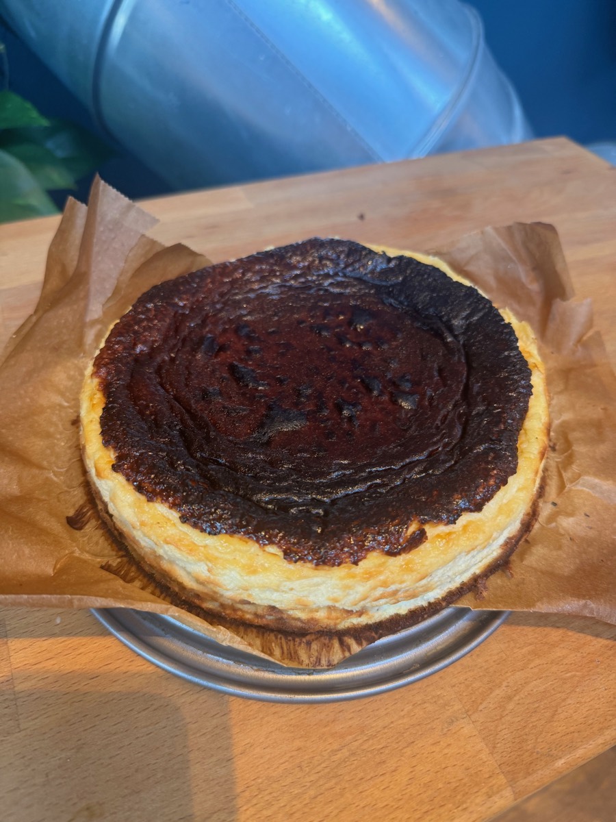 Whole cheesecake with a dark baked surface on baking paper